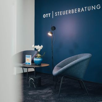 Wartebereich der Ott Steuerberatung in Weinstadt mit Sessel, Orchidee und Schriftzug an blauer Wand